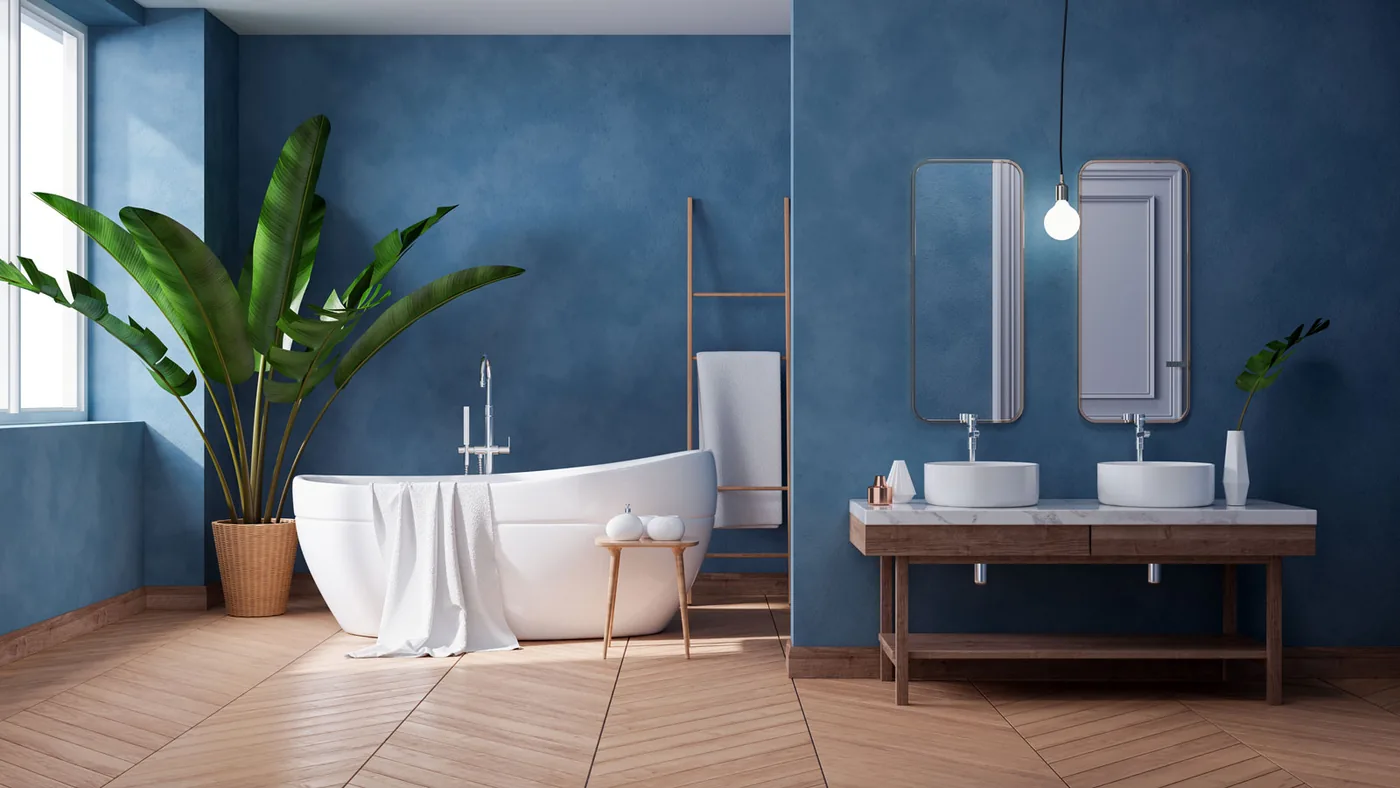 Bathroom with a deep blue feature wall, freestanding bath and herringbone timber floor